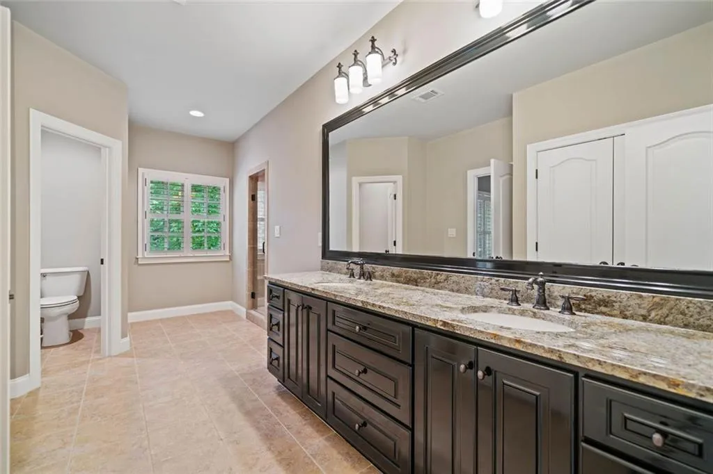 Jack and Jill bathroom with dual vanities, a shower with bench, separate water closet and a huge linen closet.