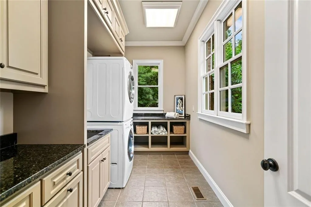 Adjacent to the mudroom, the laundry room features a utility sink, abundant cabinetry, and ample storage.