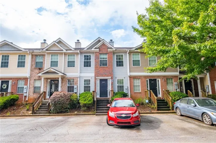 Multi-story townhome featuring brick and siding exterior, a gabled roofline, and established landscaping