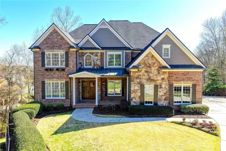 Craftsman house featuring a front yard, a standing seam roof, brick siding, and stone siding