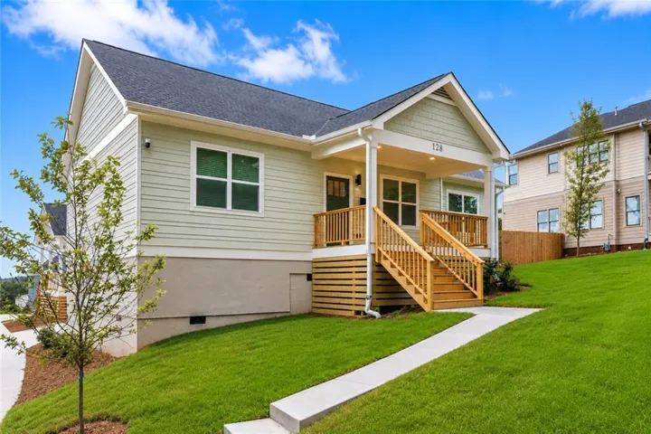 Contemporary home with light green siding, a covered porch, and a gabled entry