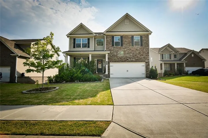 Two-story residence featuring a brick and siding facade, a double-car garage, and a covered front porch