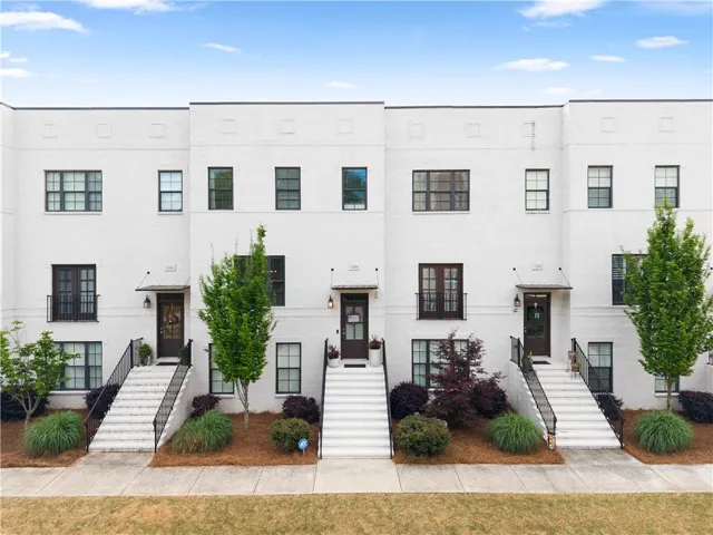 White brick exterior with dark-framed windows, black railings, and covered entryways