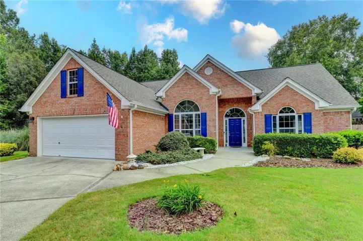Brick exterior featuring arched windows with blue shutters, a blue front door, and an attached garage with a white door