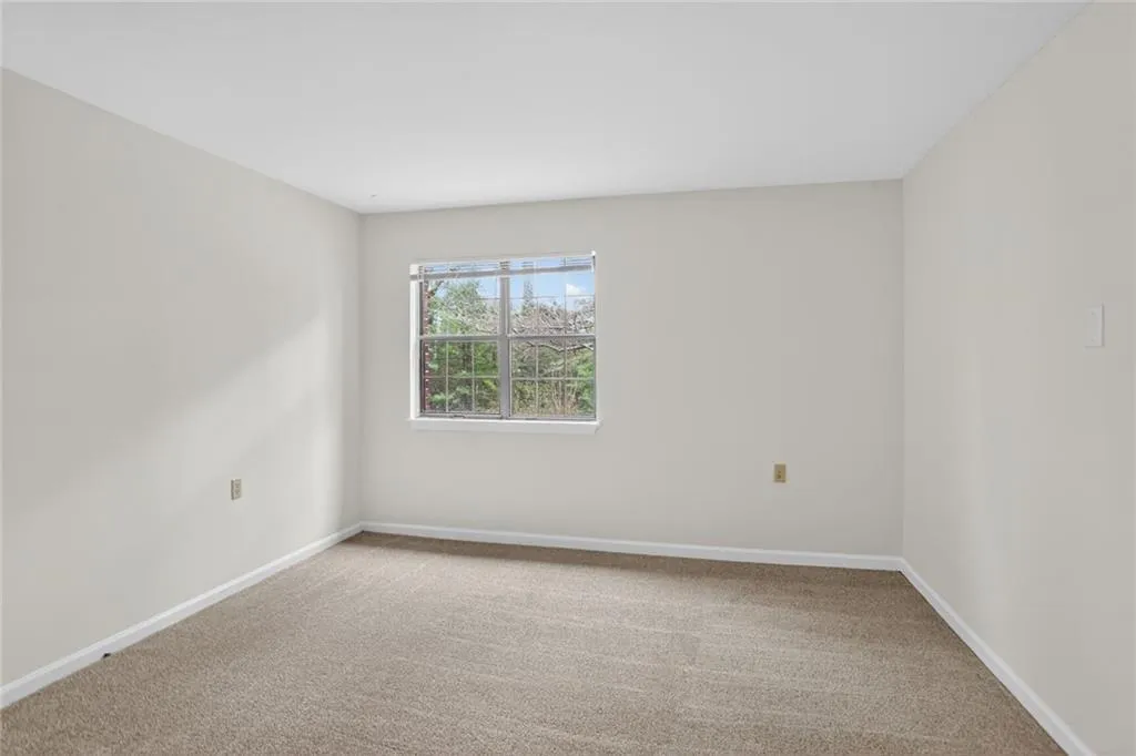 Empty room with light colored carpet and baseboards