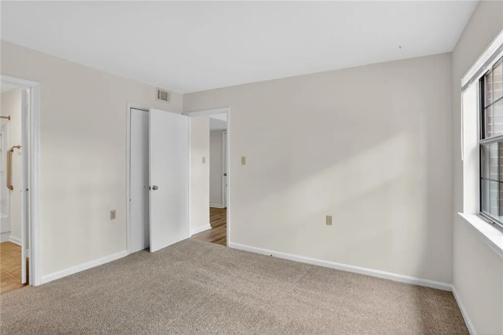 Unfurnished bedroom with light carpet and ensuite bathroom