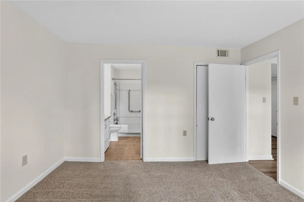 Unfurnished bedroom with light colored carpet and ensuite bath