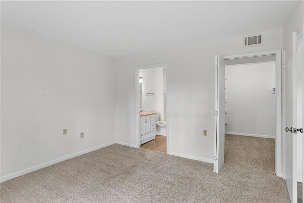 Unfurnished bedroom with light colored carpet and ensuite bath