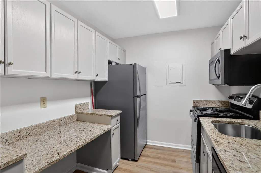 Kitchen with stainless steel appliances, light wood finished floors, and light stone countertops