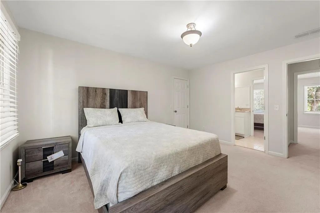 Bedroom featuring light colored carpet, baseboards, and ensuite bath