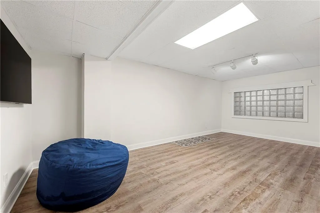 Basement featuring wood finished floors, baseboards, and rail lighting