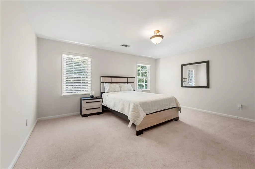 Bedroom with multiple windows, baseboards, and light carpet