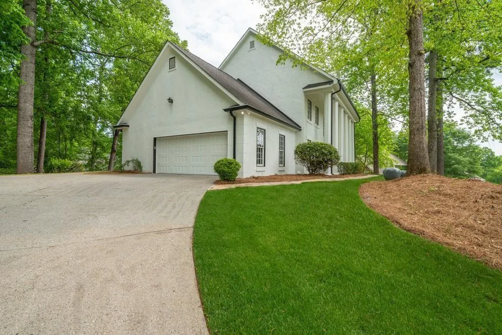 View of front of home with stucco siding, driveway, a garage, and a front yard