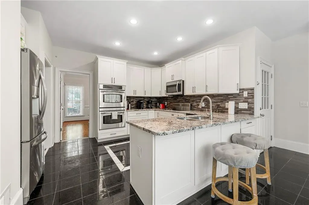 Kitchen featuring stainless steel appliances, a peninsula, decorative backsplash, white cabinets, and recessed lighting