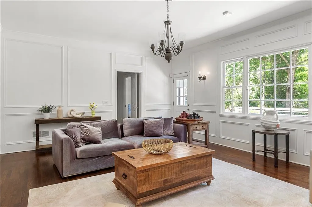 Living area with a decorative wall, a chandelier, and wood finished floors
