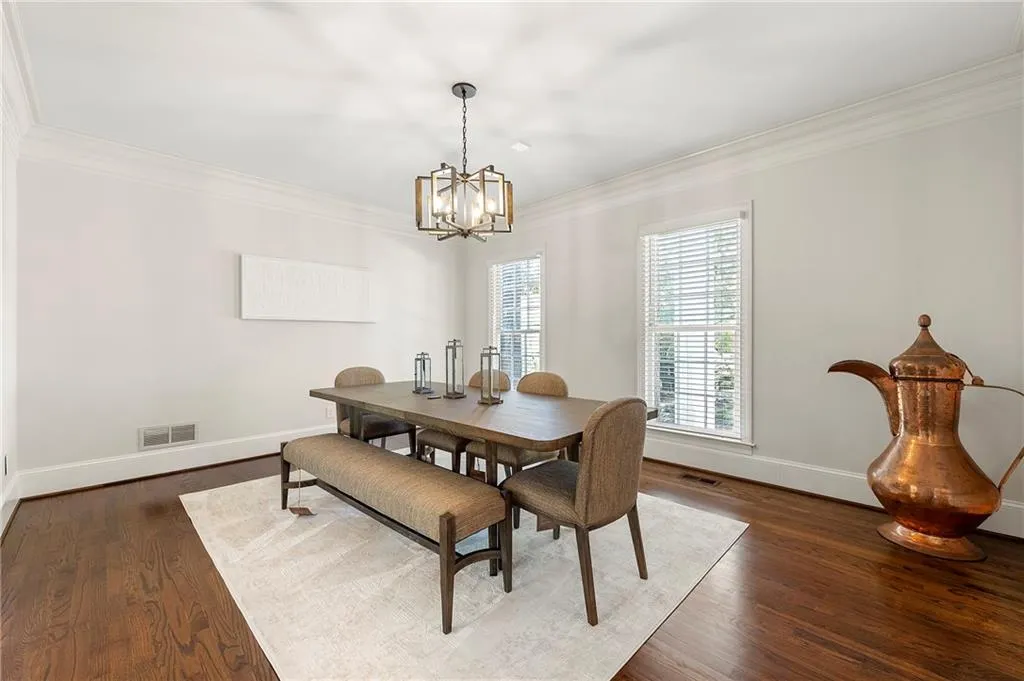Dining room featuring crown molding, a chandelier, baseboards, and dark wood-type flooring