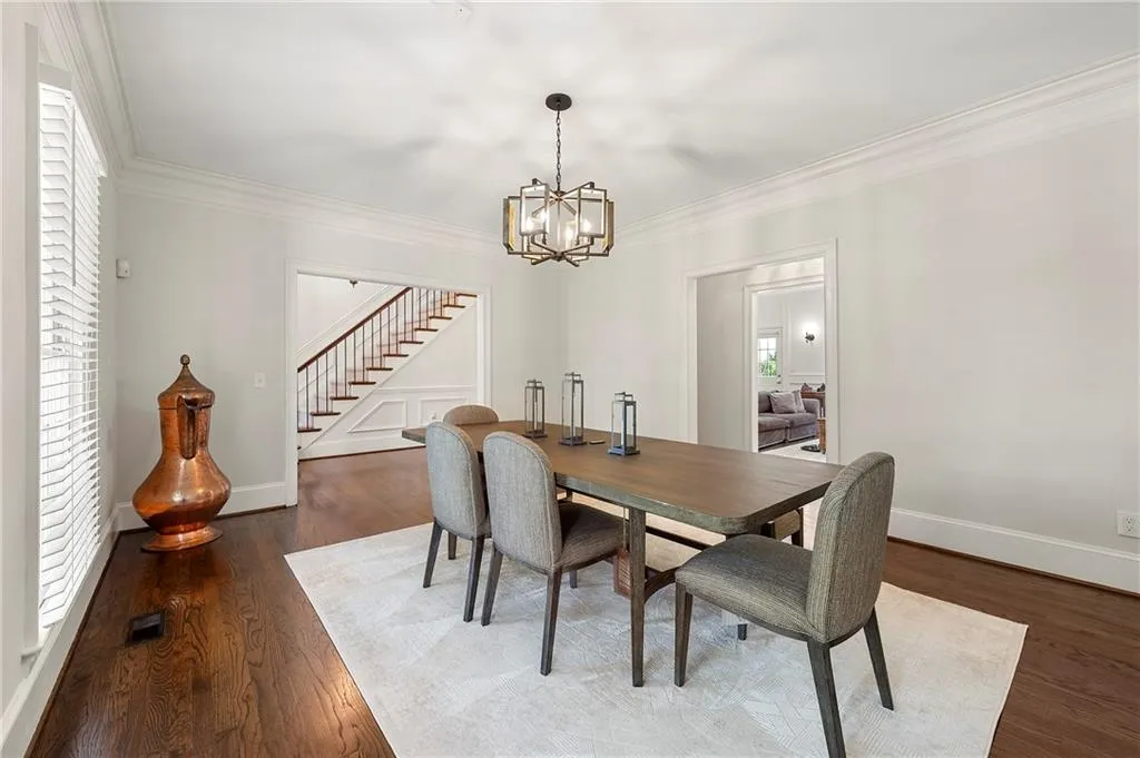 Dining space featuring stairs, a chandelier, crown molding, baseboards, and wood finished floors
