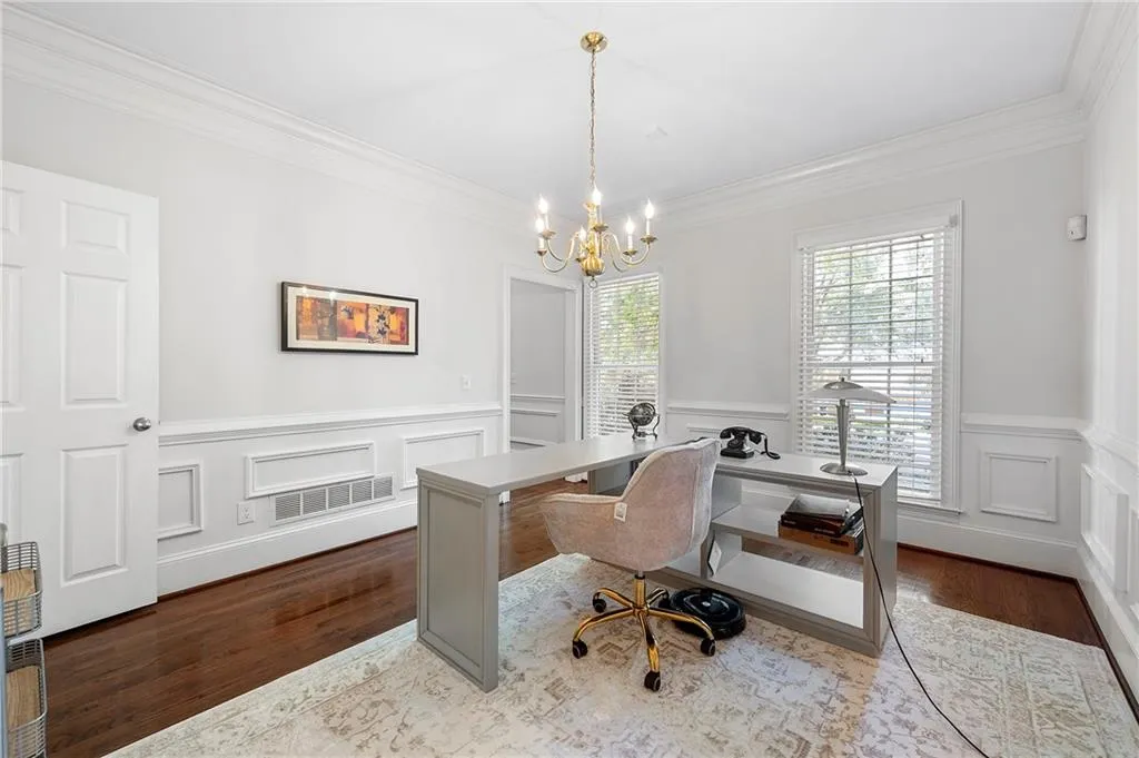 Office area with crown molding, a chandelier, wood finished floors, wainscoting, and a decorative wall