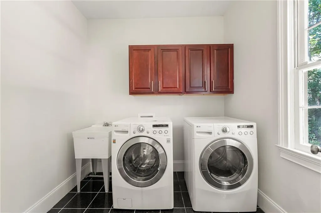 Washroom featuring washing machine and clothes dryer, baseboards, cabinet space, and dark tile patterned floors