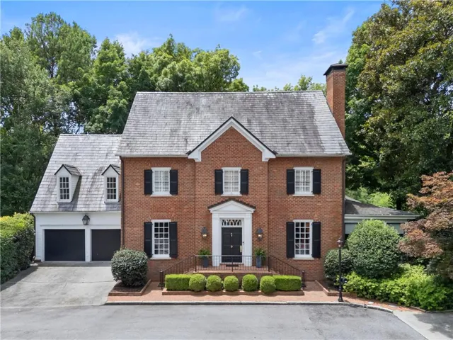 Brick exterior featuring a gabled roof and black shutters