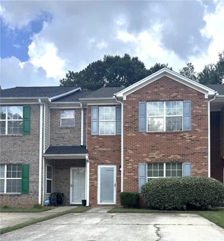 Brick and siding townhouse exterior featuring gabled rooflines, contrasting window shutters, and a covered entryway