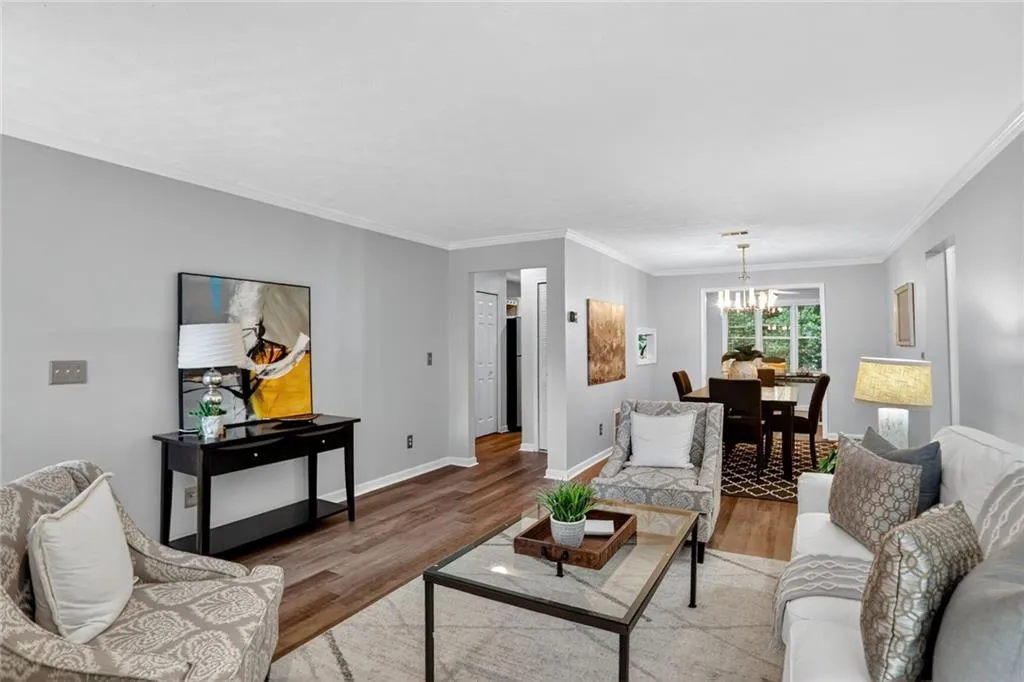 Living area with ornamental molding, light wood-style flooring, and a chandelier