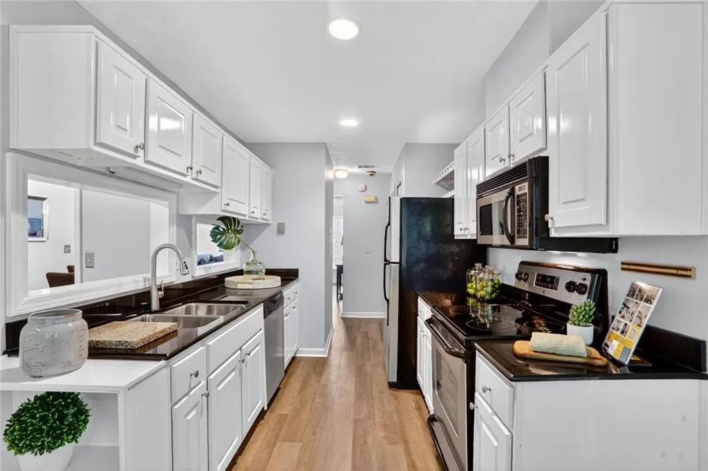 Kitchen featuring stainless steel appliances, white cabinets, light wood-style flooring, recessed lighting, and dark countertops