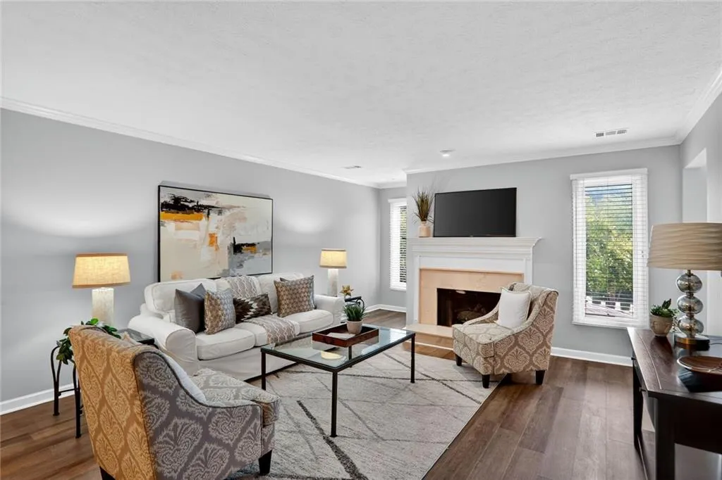 Living area with ornamental molding, a fireplace, wood finished floors, and a textured ceiling