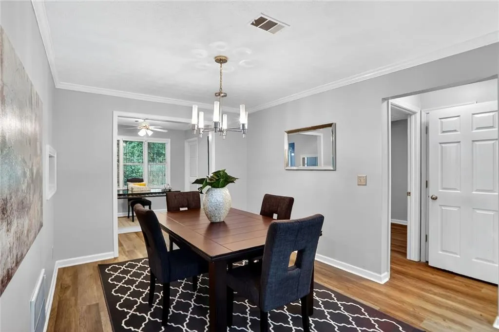 Dining room with crown molding, wood finished floors, a chandelier, and a ceiling fan