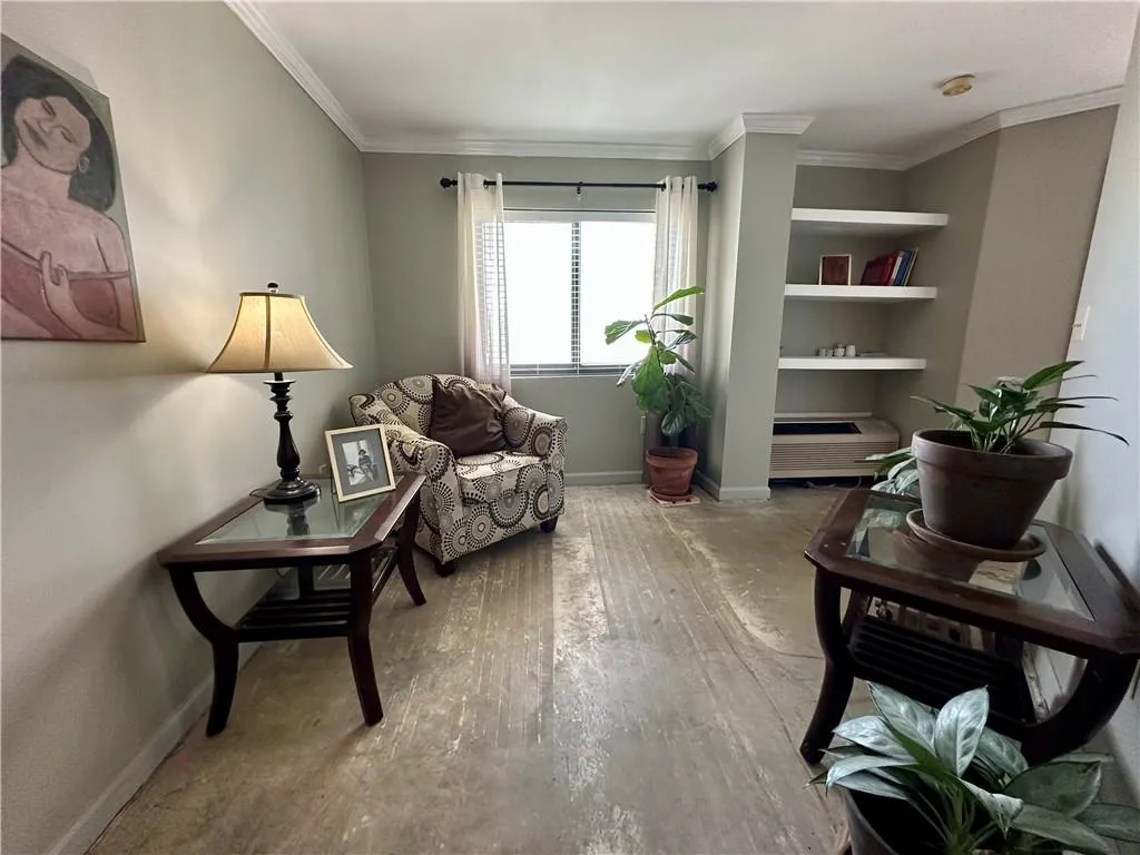 Living area with ornamental molding and built in shelves