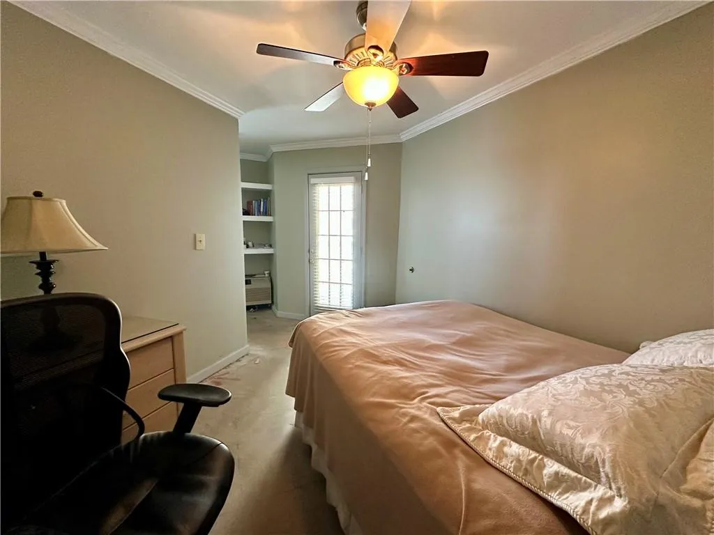 Bedroom featuring crown molding, ceiling fan, an office area, and carpet flooring