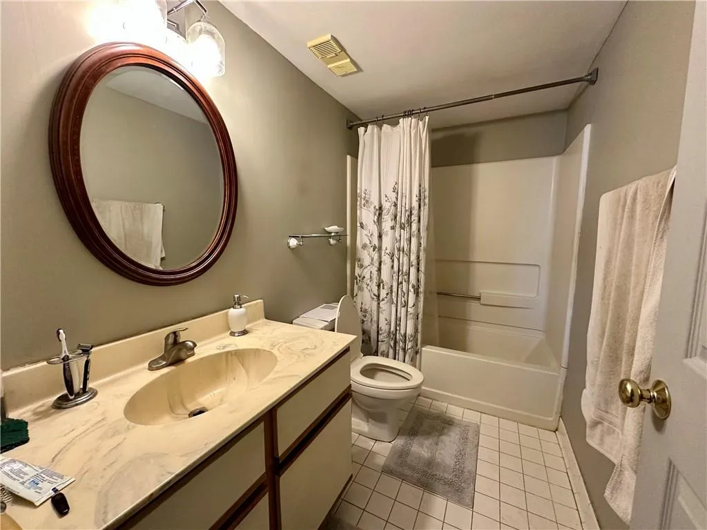 Full bathroom with vanity, shower / bathtub combination with curtain, and light tile patterned floors