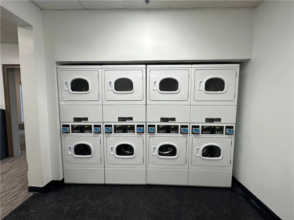 Laundry area with stacked washer and clothes dryer and a drop ceiling