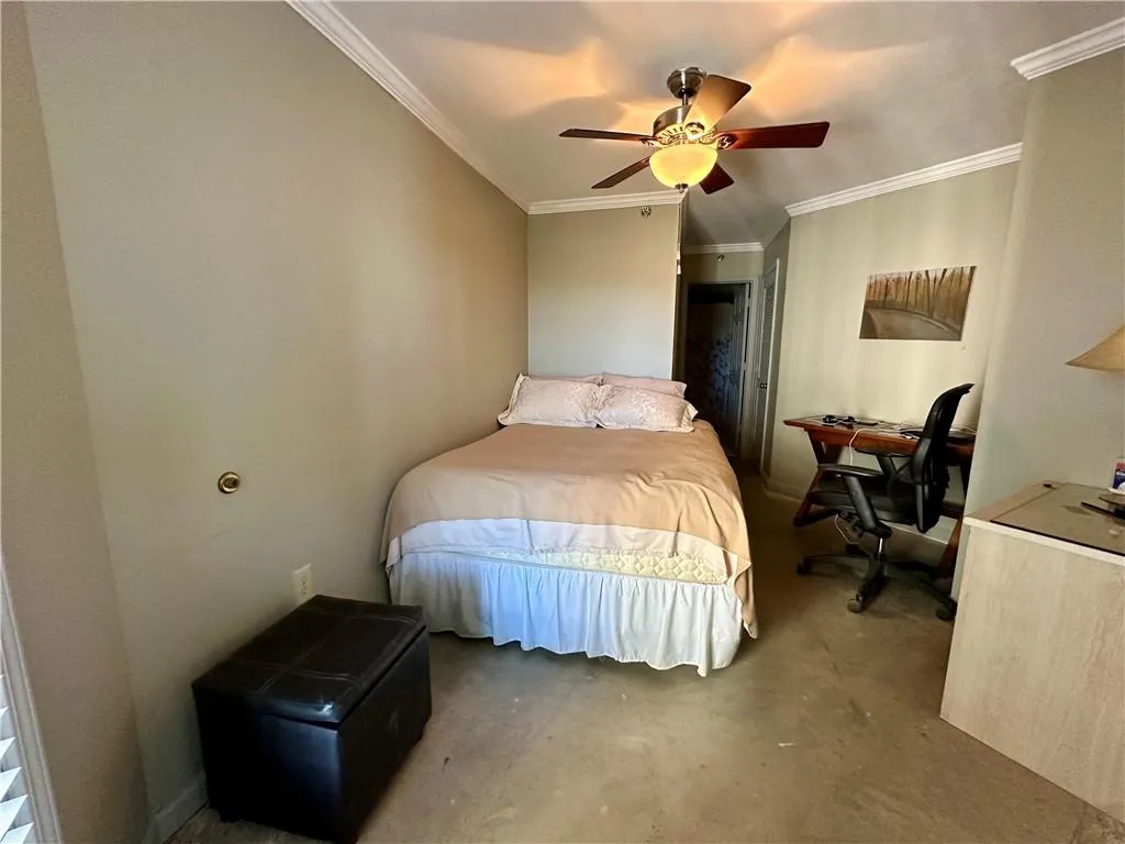 Bedroom with crown molding, ceiling fan, a desk, and concrete flooring