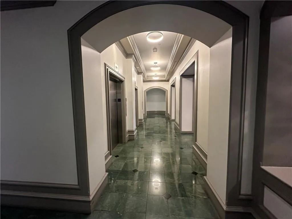 Hallway featuring arched walkways, elevator, and ornamental molding