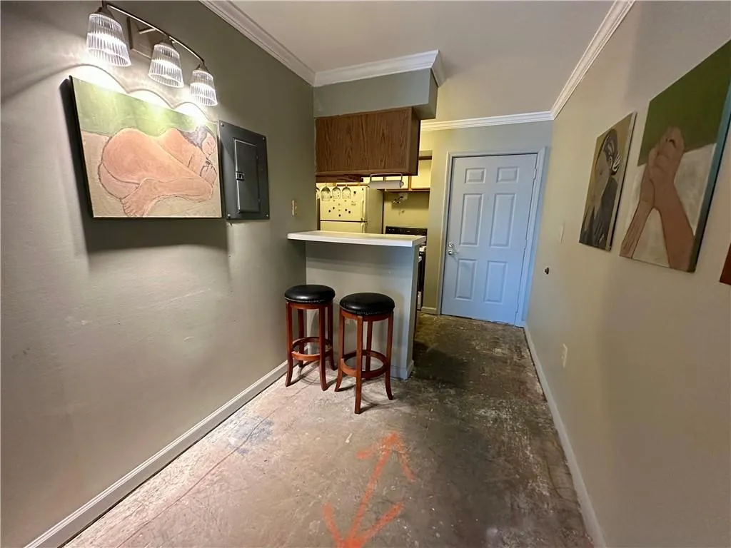 Bar with light countertops, electric panel, freestanding refrigerator, and crown molding