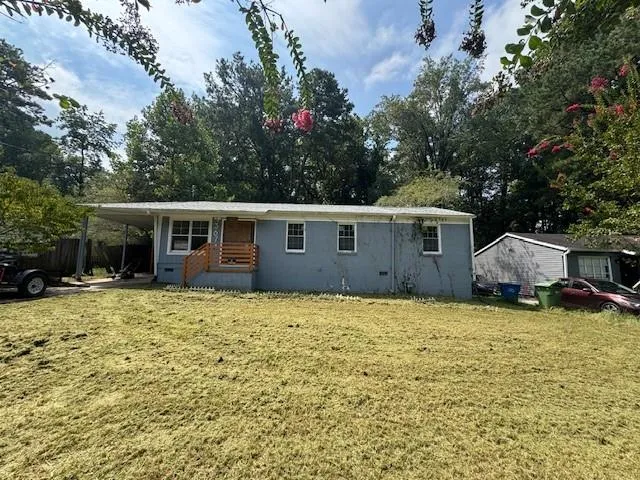 Ranch-style home featuring a front lawn, an attached carport, and covered porch