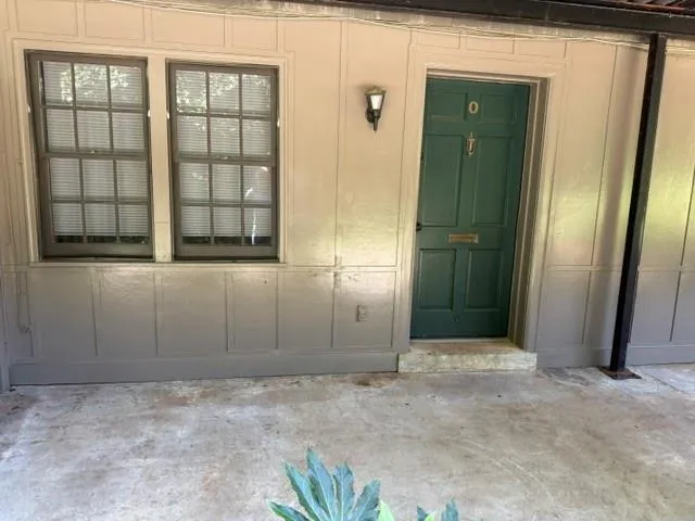 Panel siding exterior with a green entry door, decorative trim, and an exterior wall sconce