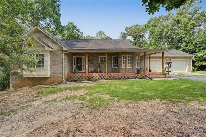 Charming brick ranch home featuring a welcoming front porch with multiple entry points, brick and siding exterior, and a detached garage