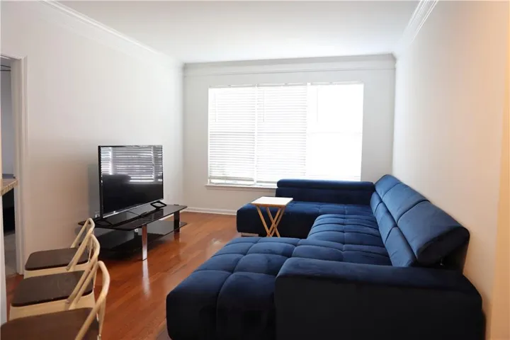 Hardwood flooring, crown molding, white wall paint, window with blinds