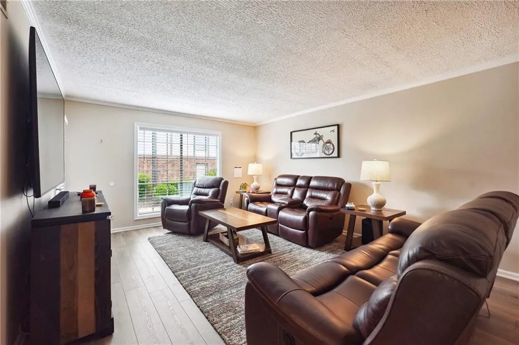 Living room with ornamental molding, dark hardwood / wood-style flooring, and a textured ceiling