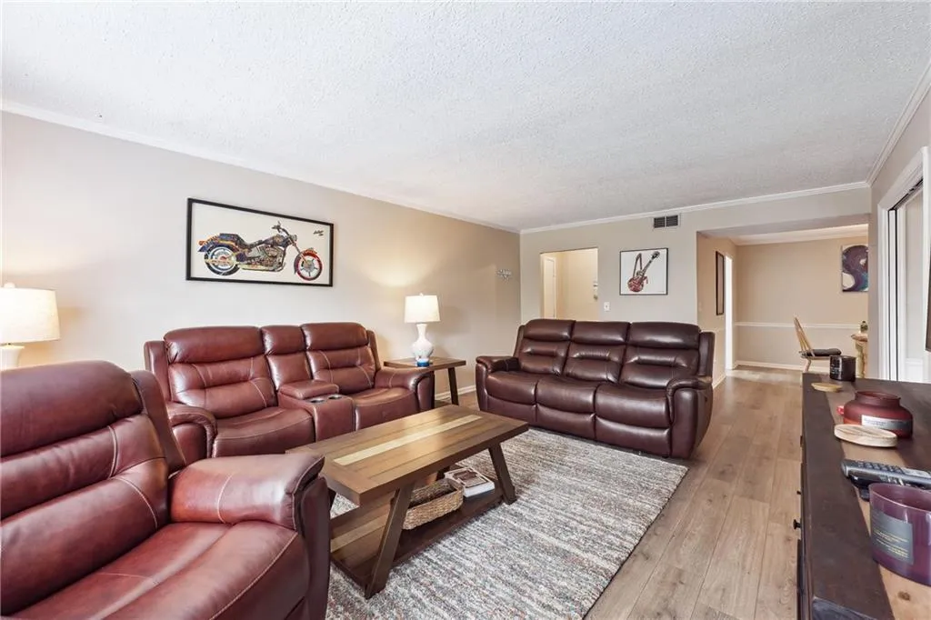 Living room featuring a textured ceiling, hardwood / wood-style flooring, and ornamental molding