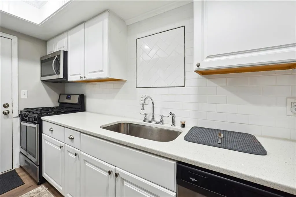 Kitchen featuring white cabinets, dark hardwood / wood-style flooring, stainless steel appliances, sink, and tasteful backsplash