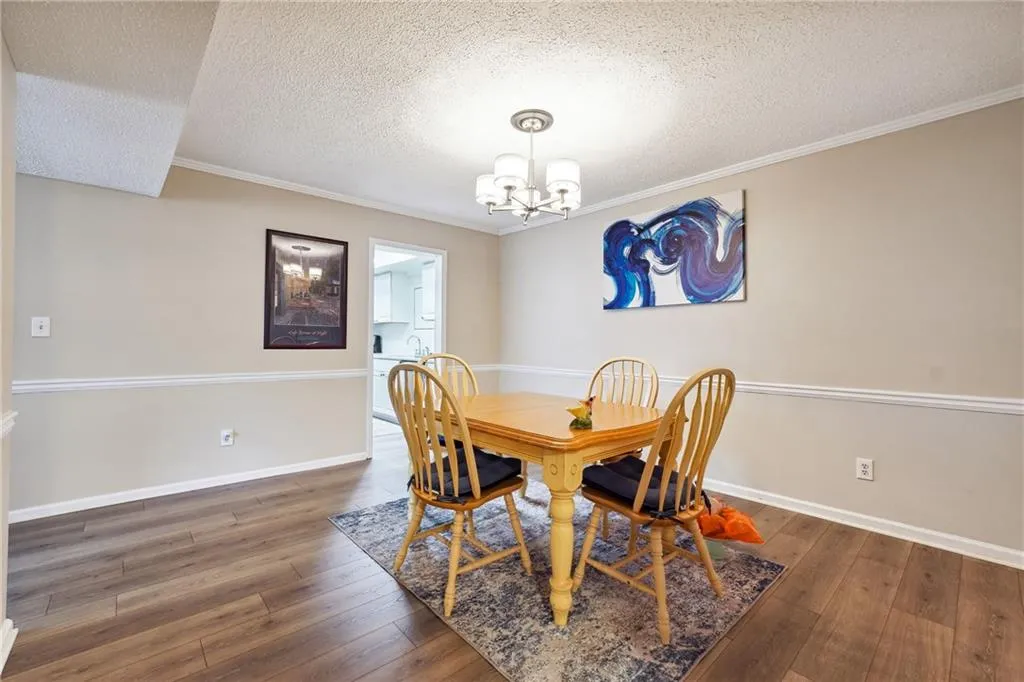 Dining space featuring a notable chandelier, crown molding, dark hardwood / wood-style floors, and a textured ceiling