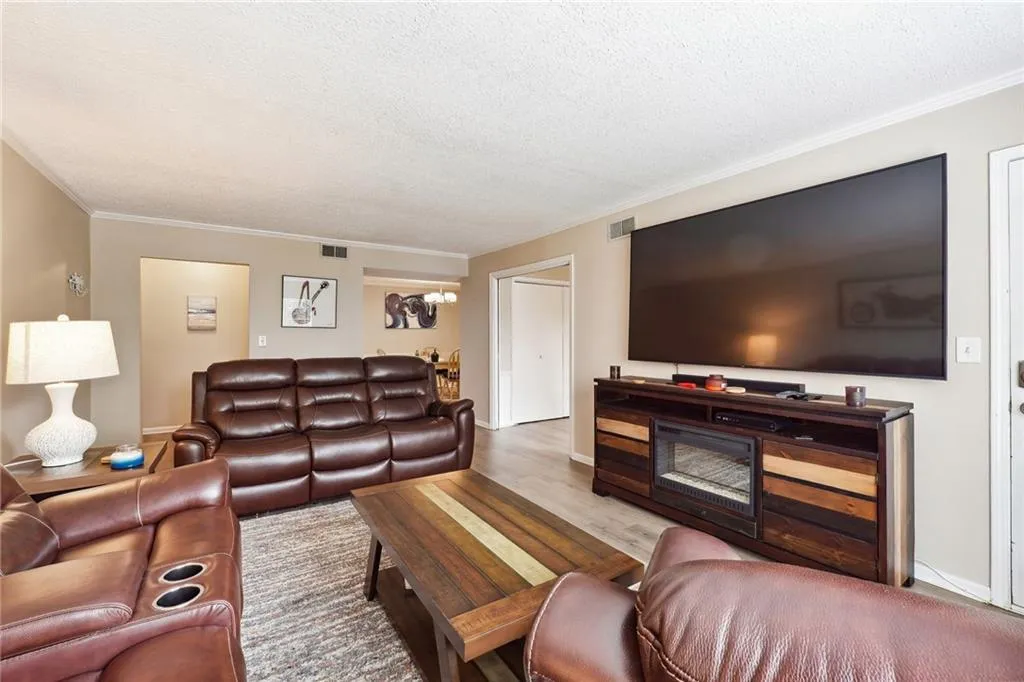 Living room featuring wood-type flooring, crown molding, and a textured ceiling