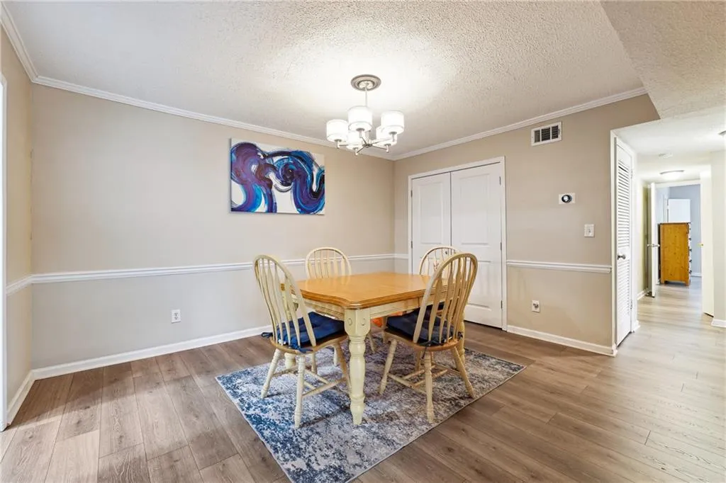 Dining area featuring ornamental molding, an inviting chandelier, wood-type flooring, and a textured ceiling