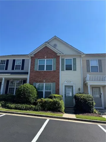 Brick and siding exterior, gabled roofline, decorative window shutters, landscaped front entry, and paved parking area