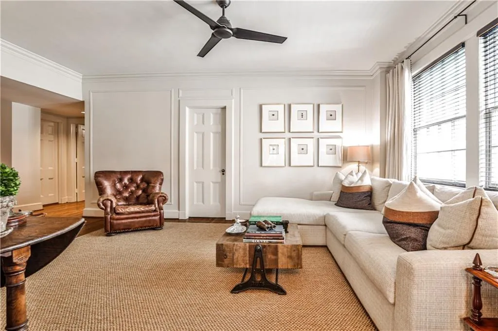 Living room featuring a ceiling fan and ornamental molding