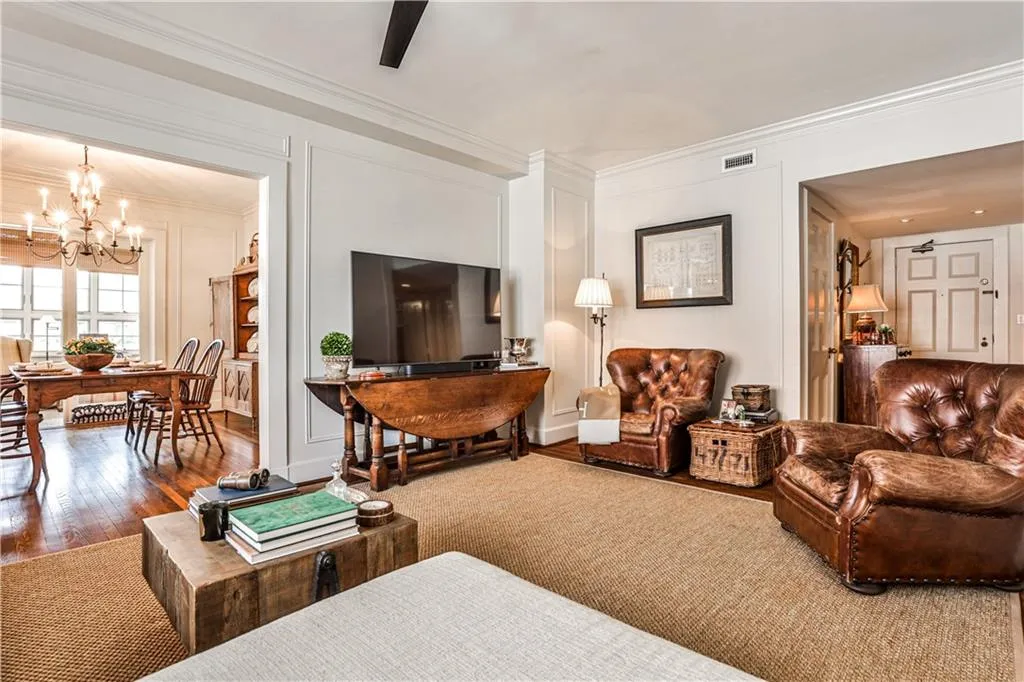 Living room with a chandelier, wood finished floors, and ornamental molding