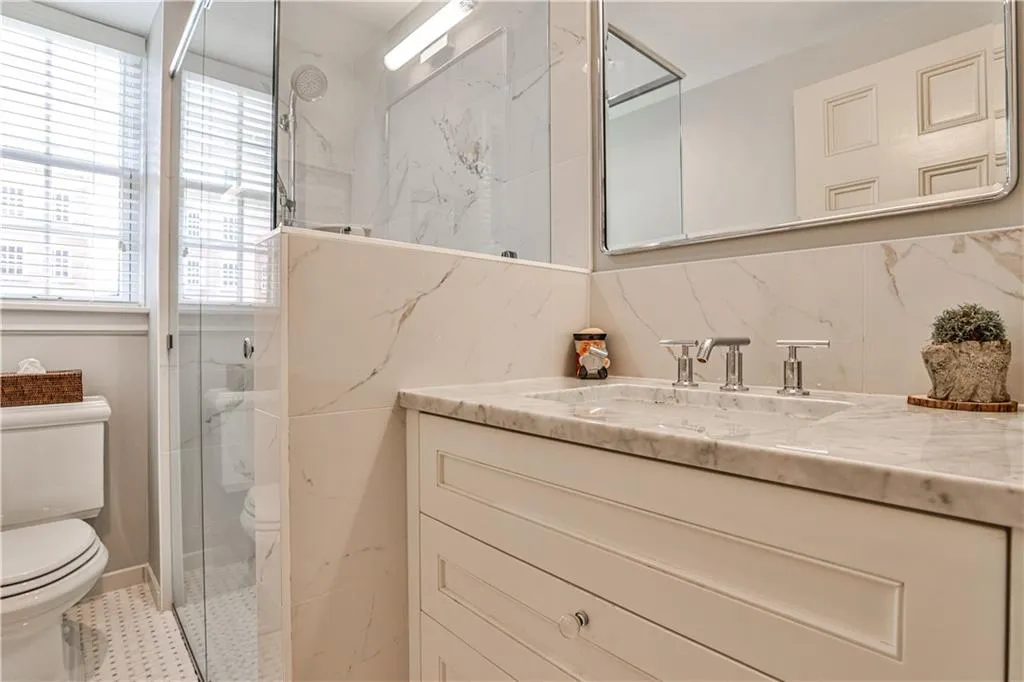 Bathroom featuring vanity and a marble finish shower